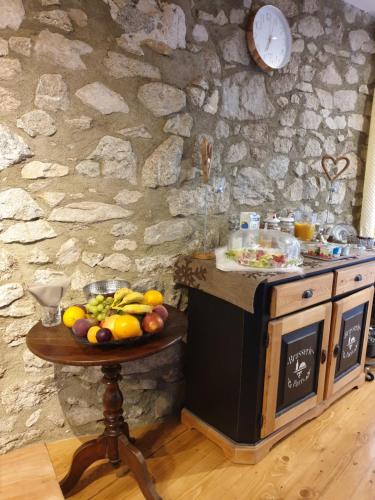 a table with fruit on it next to a stone wall at La Petite Chapelle in Font-Romeu