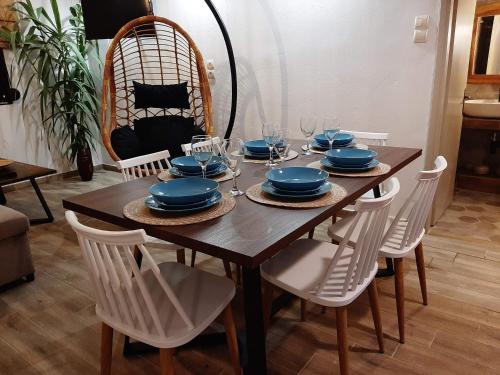 a wooden table with white chairs and blue dishes on it at Σιντηίς- Sinties in Moudhros