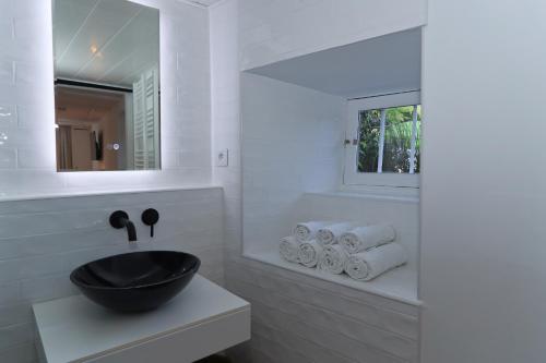 a white bathroom with a black sink and towels at Artist Flat Saint Flour in Saint-Flour