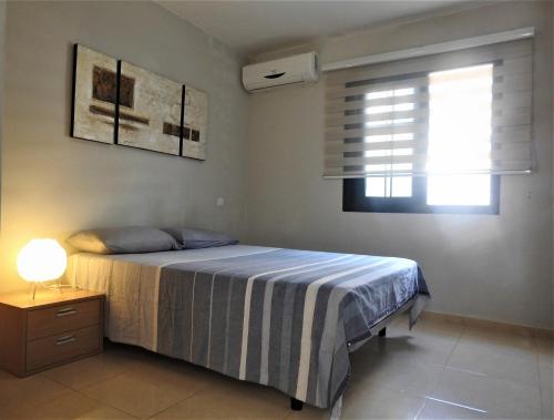 プラヤ・デル・クーラにあるApartamento Jardín Paraisoのベッドルーム1室(ベッド1台、ランプ、窓付)