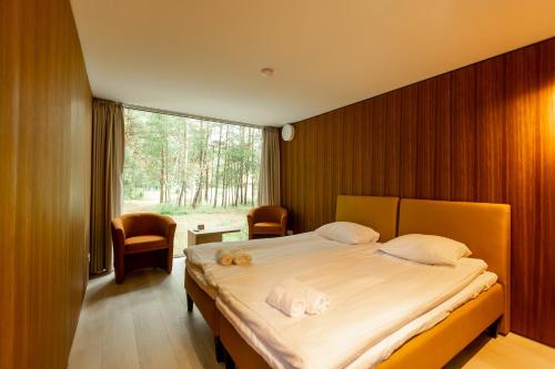 a bedroom with a large bed and a large window at Hotel Palanga Camping in Palanga