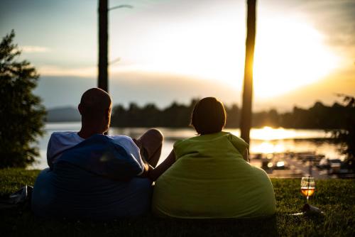 two people sitting on the grass watching the sunset at Lipno Club in Frymburk