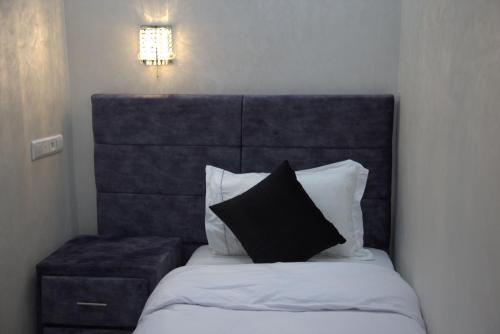 a bed with a black headboard and a black pillow at Dakhla Guest in Dakhla