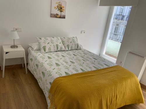1 dormitorio con 1 cama con manta amarilla y ventana en Piso en el centro para 4 personas - Plaza Amboage - WIFI, en Ferrol