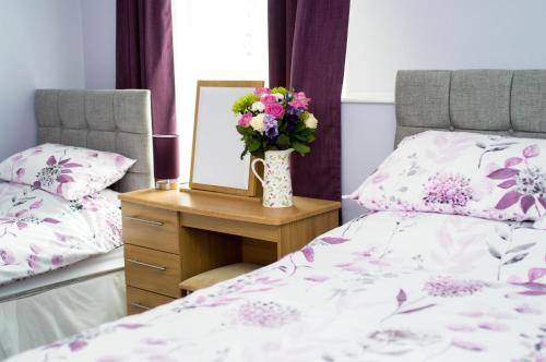a bedroom with a bed and a mirror and a vase of flowers at Aden House Bed And Breakfast in Mintlaw