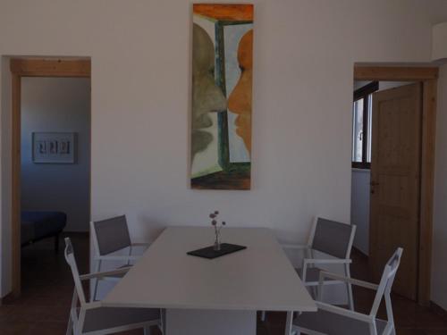 a white table and chairs in a room with a painting at Stazzu Giasti Agriturismo in Aglientu