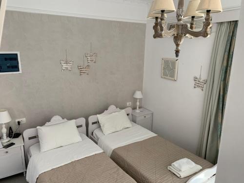 a bedroom with two beds and a chandelier at Blue Sea Hotel in Kamari