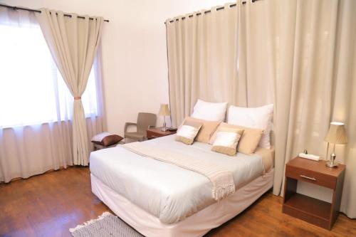um quarto com uma cama com lençóis brancos e almofadas em Union Guesthouse em Pretoria