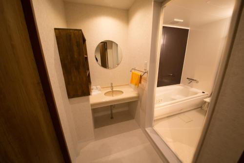 a bathroom with a sink and a tub and a mirror at City Kaigetsu in Sumoto