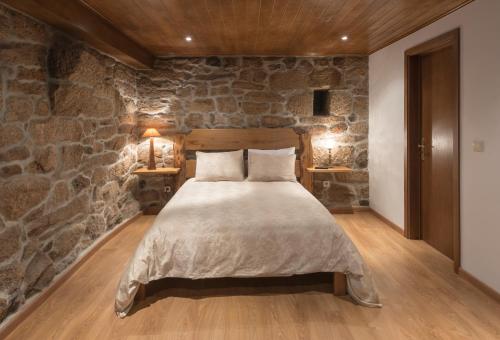 a bedroom with a large bed in a stone wall at Casa Da Laborada in Vilar de Perdizes