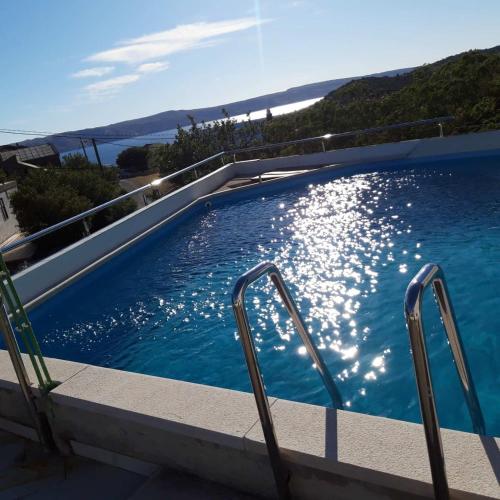 a swimming pool with two chairs in the water at Apartmani CESARICA in Karlobag