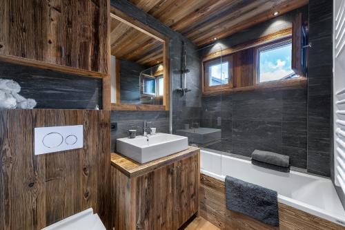 a bathroom with wooden walls and a sink and a tub at MEGEVE Jaillet 3 chambres 6 personnes in Megève