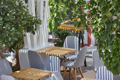 a patio with tables and chairs and trees at Blue Sea Hotel in Kamari