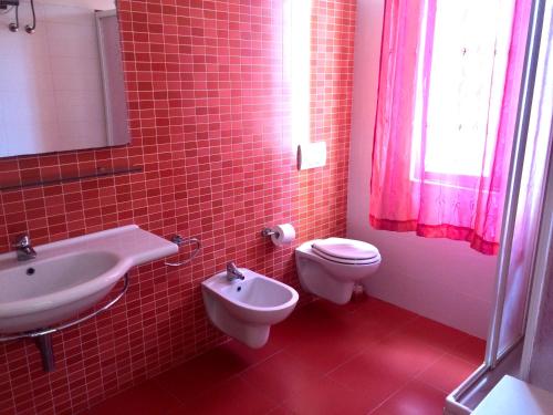 baño de azulejos rojos con aseo y lavamanos en Appartamenti Venere, en San Vincenzo