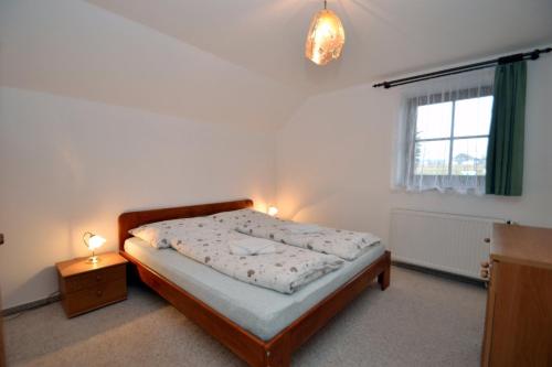 a bedroom with a bed and a window and two lamps at Apartmány Florian in Frymburk