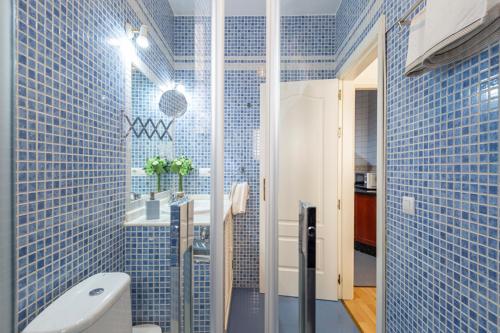 La salle de bains est pourvue de carrelage bleu, de toilettes et d'un lavabo. dans l'établissement Homefeel Museo, à Séville