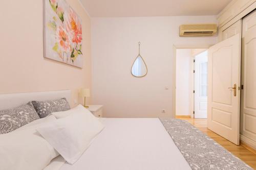 a white bedroom with a white bed and a door at Homefeel Museo in Seville