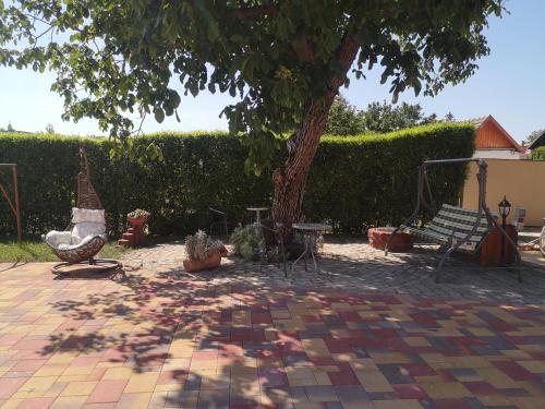 a patio with a tree and chairs and a table at Szent István Wellness Panzió in Makó