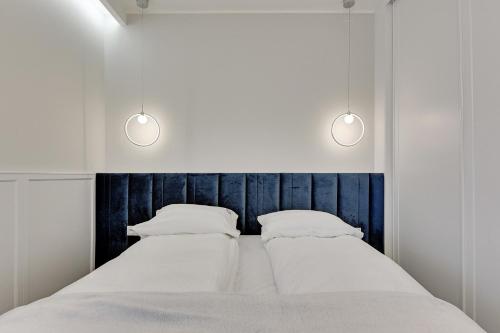 a bed with two pillows and two lights above it at Grand Apartments - Indygo Okrzei Residence Sopot in Sopot