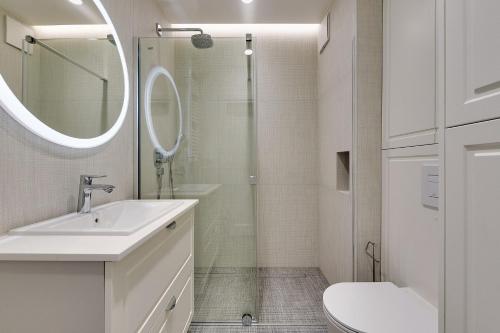 a white bathroom with a sink and a shower at Grand Apartments - Indygo Okrzei Residence Sopot in Sopot