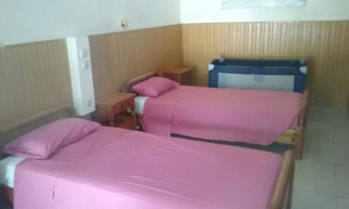 two beds in a room with pink sheets at Kitesurf Paradise Studios in Theologos