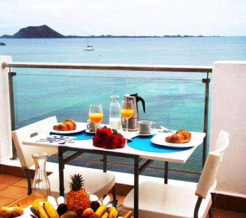 una mesa con comida y bebida en un balcón con vistas al océano en On the beach, en Corralejo