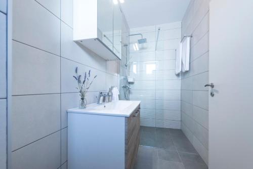 een witte badkamer met een wastafel en een spiegel bij Holiday Home Lana in Supetar