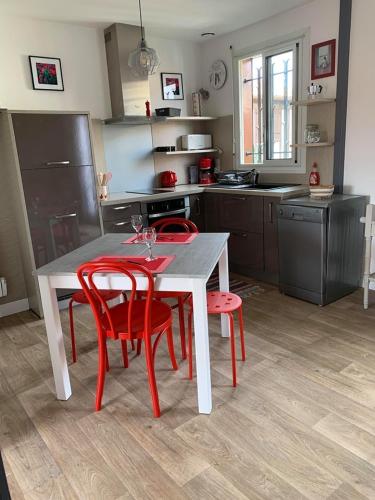 une cuisine avec une table et quatre chaises rouges dans l'établissement Appartement Résidence Saint Jours - Centre ville, à Vieux-Boucau-les-Bains