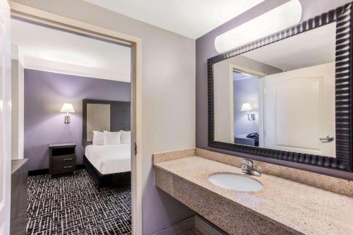 a bathroom with a sink and a mirror and a bed at La Quinta by Wyndham Fultondale Birmingham North in Fultondale