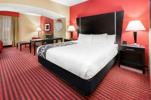 a hotel room with a large bed and red walls at La Quinta by Wyndham Boutte in Boutte