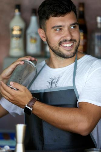 a man wearing an apron holding a metal item at Blue Sea Hotel in Kamari
