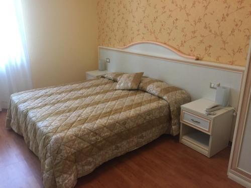 una camera con letto e comodino con un letto sidx sidx sidx. di Albergo La Pineta a Cingoli