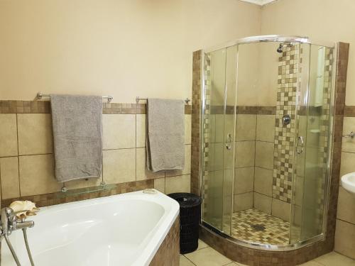 a bathroom with a tub and a glass shower at Numbi Hills Self-Catering in Hazyview