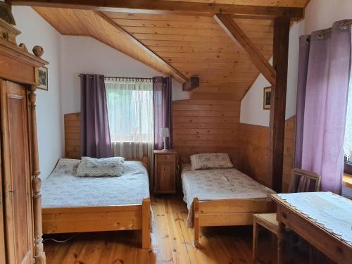 um quarto com 2 camas numa casa de madeira em Siedlisko nad Sapiną em Kruklanki