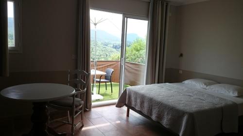 a bedroom with a bed and a table and a window at Au Relais Provencal in Bagnols-en-Forêt