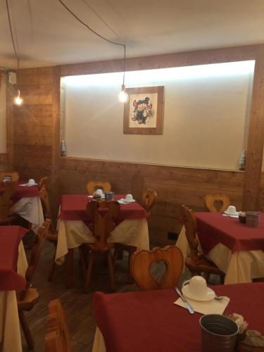 a restaurant with tables and chairs with red table cloth at Green Hotel Herbetet in Cogne