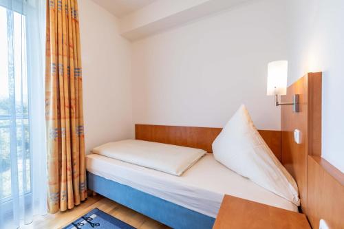 a small bed in a room with a window at Gasthaus Hotel Ostermeier in Attenkirchen