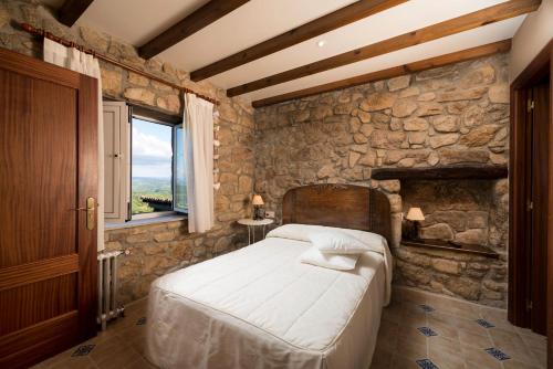 1 dormitorio con cama y pared de piedra en Aldeade, en Ferreira