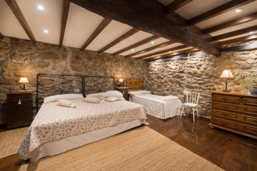 a bedroom with two beds and a stone wall at Aldeade in Ferreira de Panton