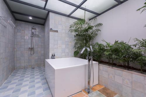 a bathroom with a shower and a white tub at Guilin Flowers Inn in Guilin
