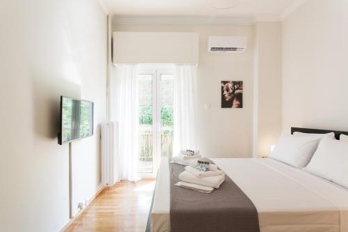 um quarto branco com uma cama e uma janela em La maison de Philopappou em Atenas