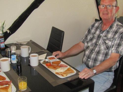 布莱克浦Alderley Hotel Blackpool的坐在桌子上拿着一盘食物的人