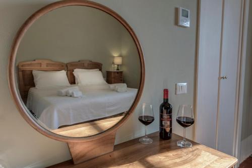 a mirror with a bed and two glasses of wine at Agriturismo La Fattoria di Capezzana in Carmignano