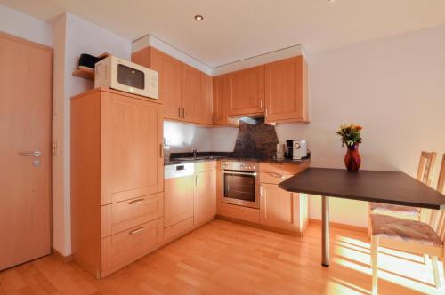 a kitchen with wooden cabinets and a table with a microwave at Haus Shangri-La in Saas-Fee