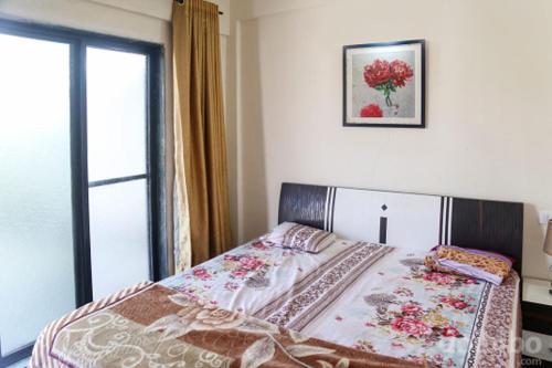 Schlafzimmer mit einem Bett und einem Fenster mit einem Bild in der Unterkunft Aryan Bungalow 4BHK in Lonavla