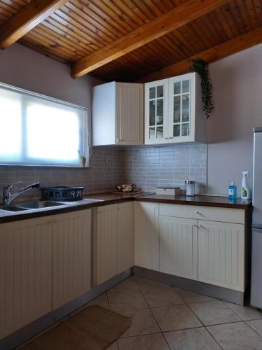 een keuken met witte kasten, een wastafel en een raam bij Vravrona Artemis Home & Transfer Airport in Artemida