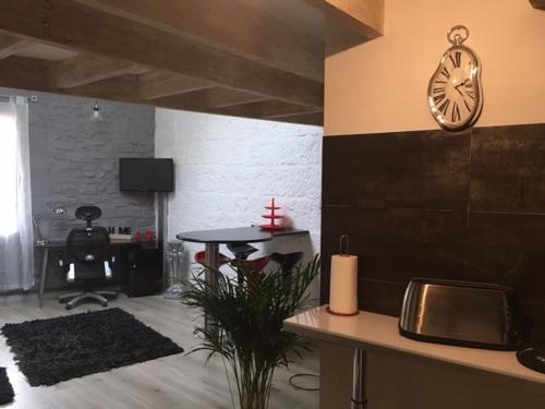 a living room with a table and a clock on the wall at Duplex au Coeur de Lunel in Lunel