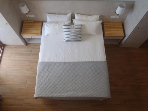 a large bed with white sheets and pillows at Loukas Apartments On The Waves in Tragaki