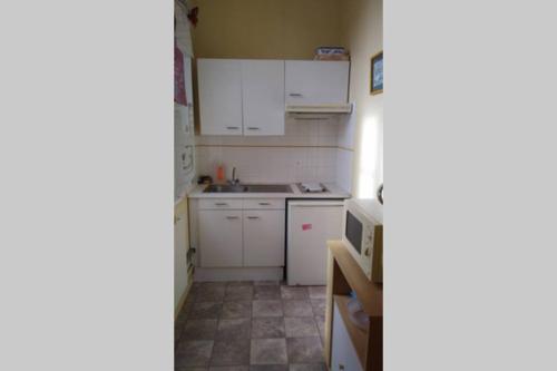 une petite cuisine avec des armoires blanches et un micro-ondes dans l'établissement appartement 60m2 dans quartier historique, à Rochefort