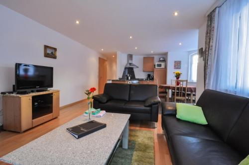 a living room with a couch and a tv at Haus Shangri-La in Saas-Fee